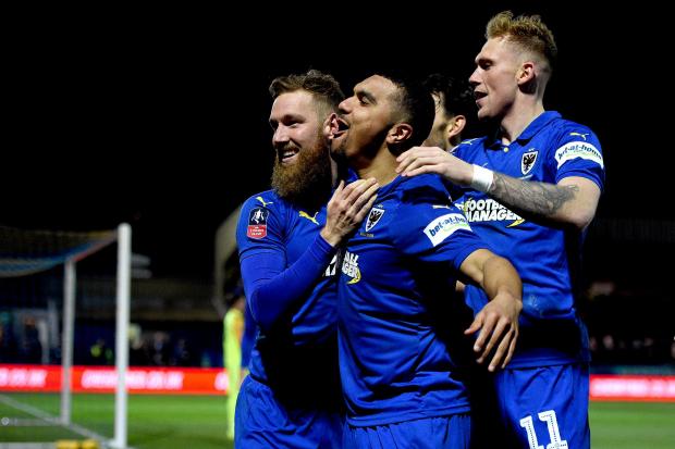 AFC Wimbledon's Scott Wagstaff celebrates scoring his side's third goal of the game with team-mate Kwesi Appiah (centre) during the FA Cup fourth round match at Kingsmeadow, London. (Photo: PA)